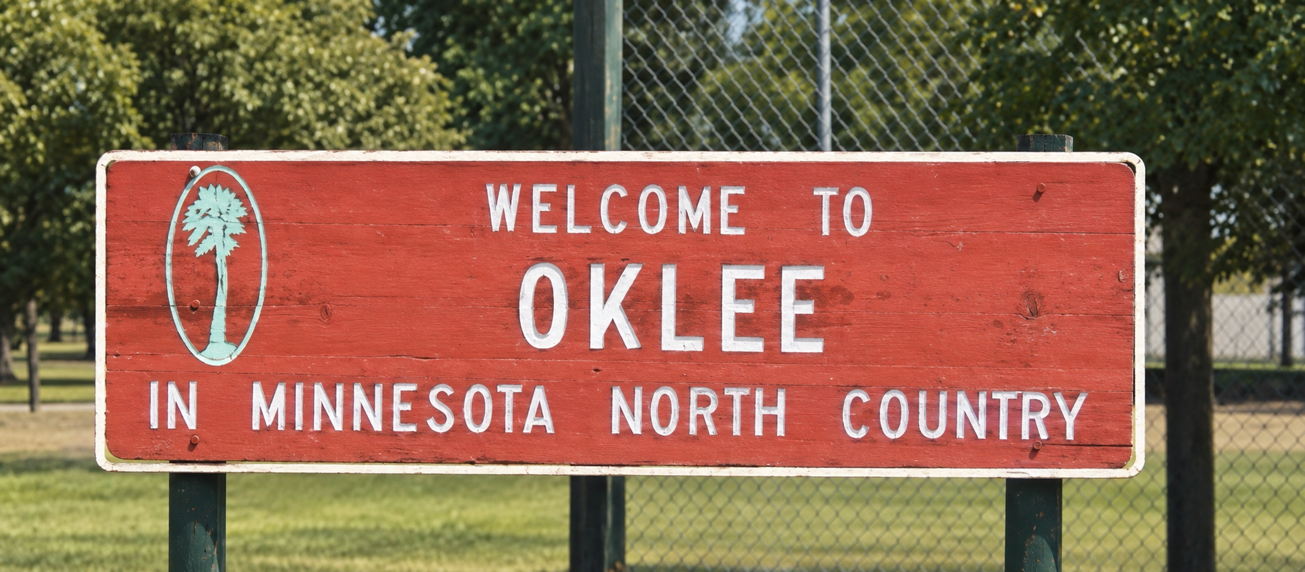 Illustrative restoration of the red Welcome to Oklee sign reading In Minnesota North Country